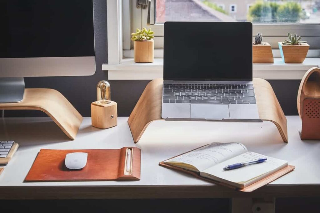 a laptop and an open journal on a white table